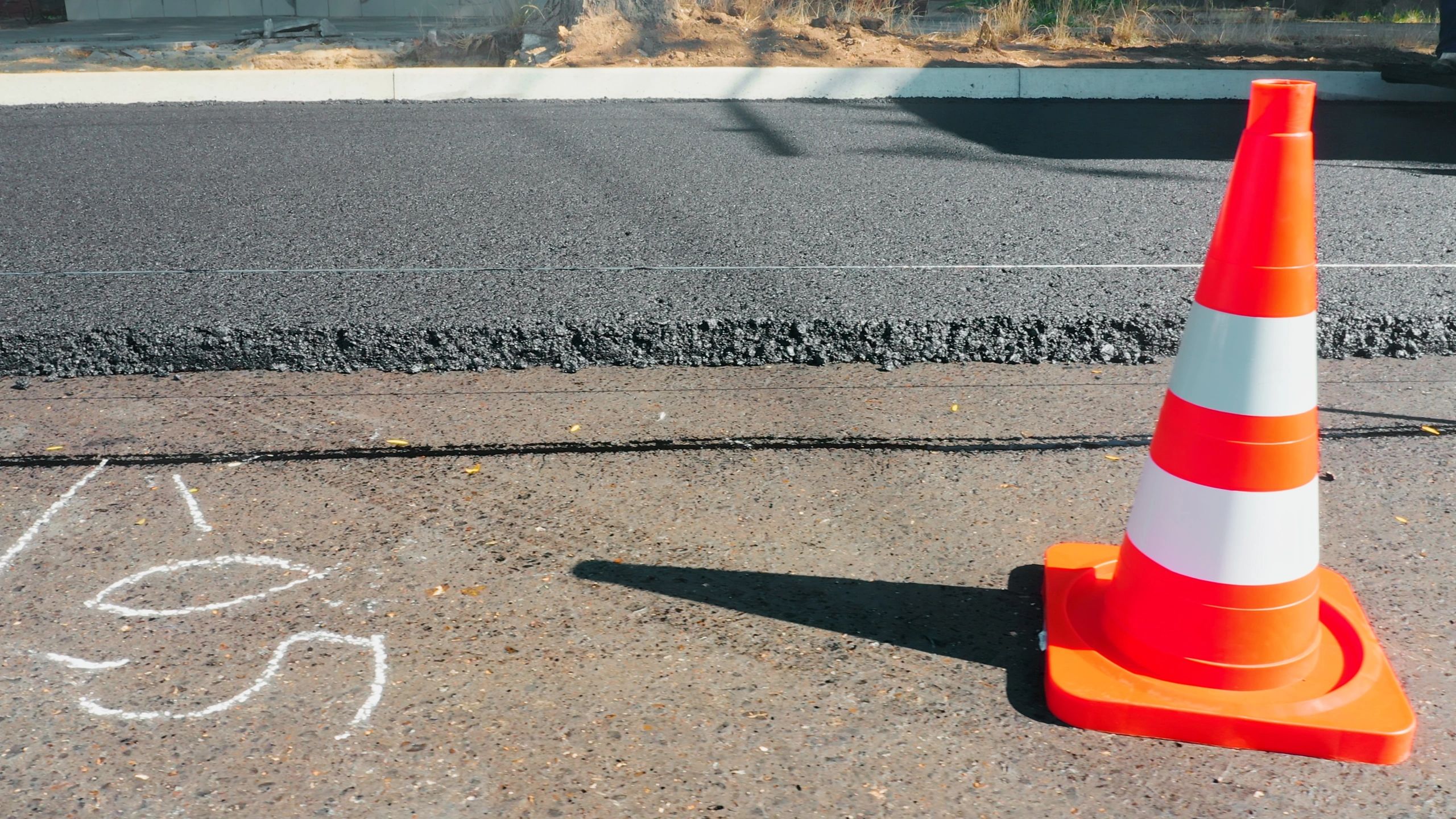 Orange traffic cone marking new asphalt road construction